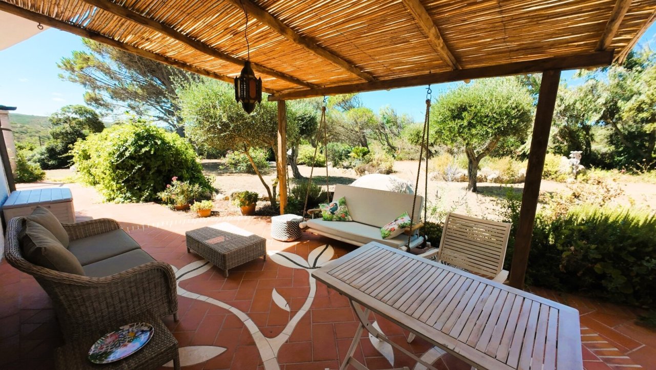 Mediterrane Wohlfühloase: Überdachte Terrasse mit Naturstein-Bodenfliesen und rustikaler Bambus-Pergola - Ihr persönliches Urlaubsparadies zum Entspannen!
