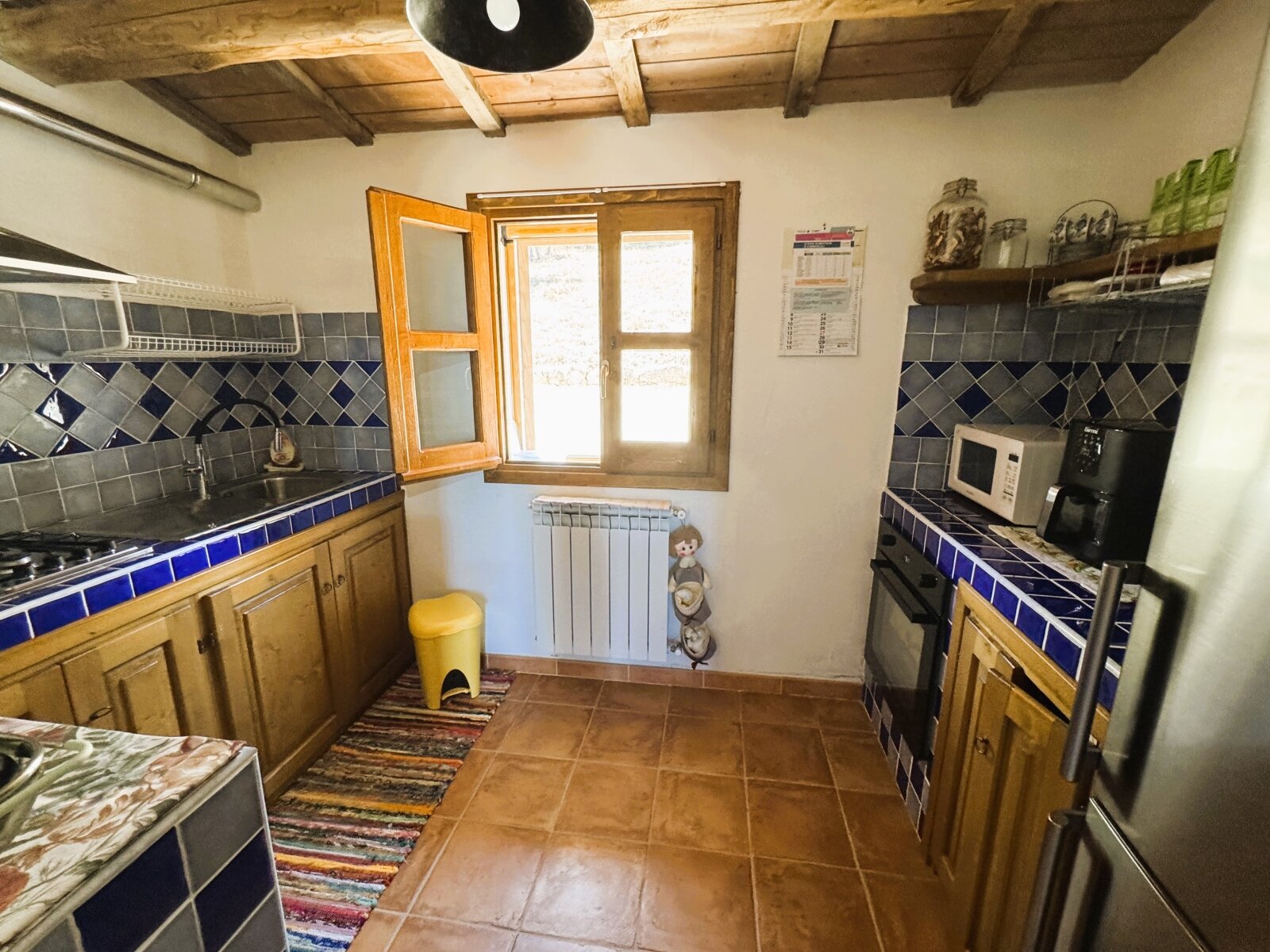 Rustikale Landhausküche mit charmantem Holzdecken-Ambiente und blau-weißer Kachel-Akzentuierung Rustikale Landhausküche mit charmantem Holzdecken-Ambiente und blau-weißer Kachel-Akzentuierung