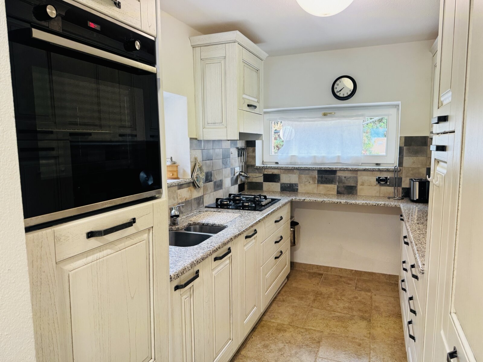 High-quality country house kitchen with comfort: built-in oven, granite countertop, and charming window placement High-quality country house kitchen with comfort: built-in oven, granite countertop, and charming window placement