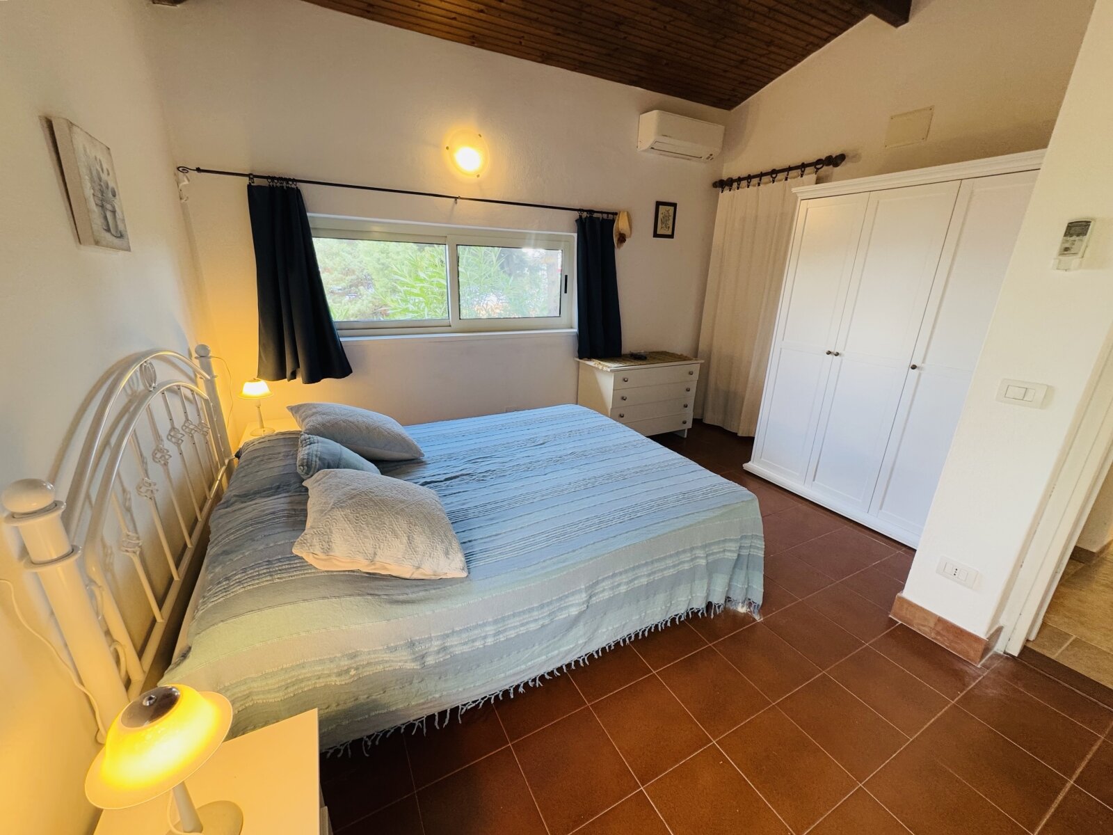 Pure comfort: bedroom with air conditioning, spacious built-in wardrobe, and charming wooden ceiling accent Pure comfort: bedroom with air conditioning, spacious built-in wardrobe, and charming wooden ceiling accent