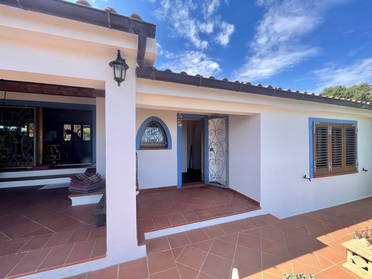 Oasi di charme mediterraneo: accogliente ingresso con porta in ferro battuto decorativa e elegante pavimentazione in terracotta Oasi di charme mediterraneo: accogliente ingresso con porta in ferro battuto decorativa e elegante pavimentazione in terracotta