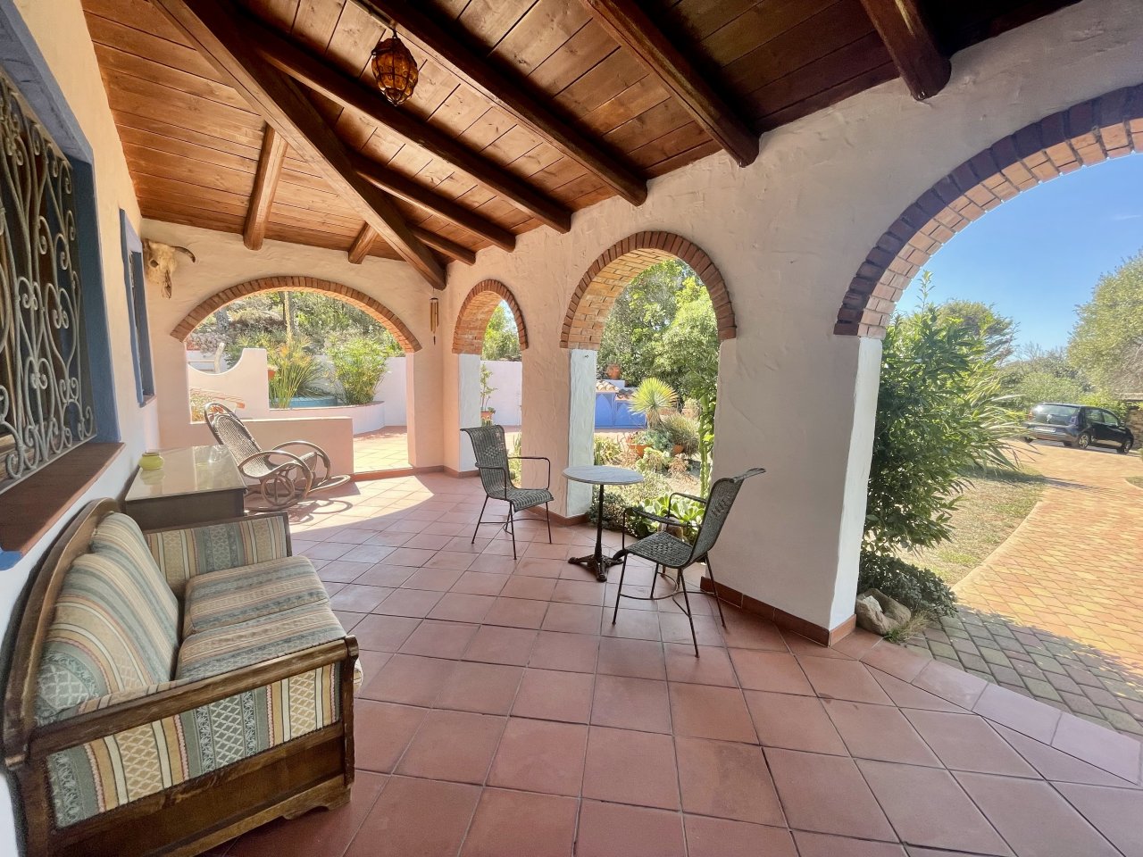 Veranda mediterranea con fascino: terrazza coperta con archi in mattoni e vista panoramica sul verde Veranda mediterranea con fascino: terrazza coperta con archi in mattoni e vista panoramica sul verde