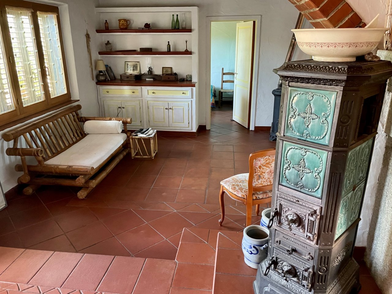 Ambiente di affascinante casa di campagna: pavimenti in terracotta rustici e un camino in maiolica nostalgico creano un comfort abitativo senza tempo Ambiente di affascinante casa di campagna: pavimenti in terracotta rustici e un camino in maiolica nostalgico creano un comfort abitativo senza tempo
